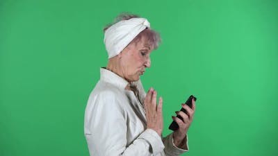 Old Stylish Woman Is Texting on Her Phone Isolated Over Green Background..