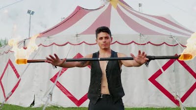 Circus artist holding burning contact fire staff.