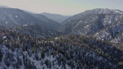 Epic Drone Pullback Flight Winter Christmas Snow-covered Mountains while snowing.