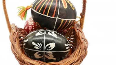Decorative Basket with Painted Easter Eggs on White Background.