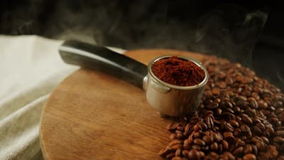 Ground Coffee in Portafilter on Wooden Board with Coffee Beans and Dissipating Steam.