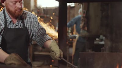 Blacksmith Tending Forge Fire in Workshop.