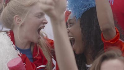 Sports enthusiasts cheering and embracing at sports match, slow motion.