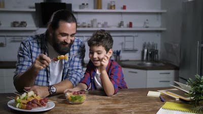 Father and Son Preparing Fruit Skewers in Kitchen.