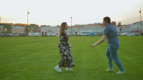 A cute couple playing on the grass.