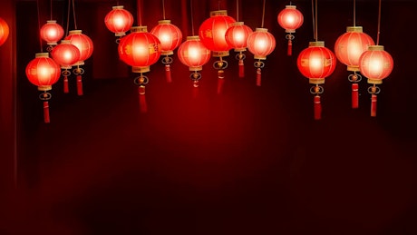 A mesmerizing display of several hanging lit red Chinese traditional lanterns move gracefully with the wind.