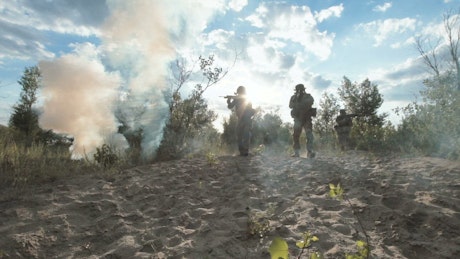 Armed soldiers walking on the field.