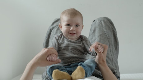 Baby on the belly of his mother plays and smiles.