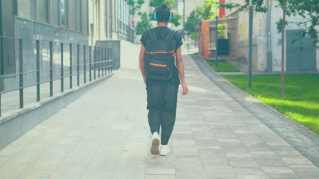 Boy walking happily down the street with headphones.