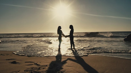 Couple holding hands on the beach.