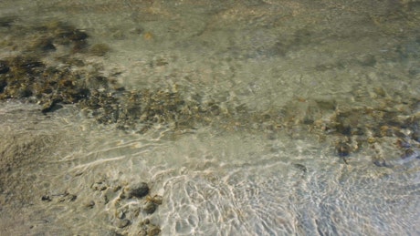 Crystal clear water flowing over the sand.