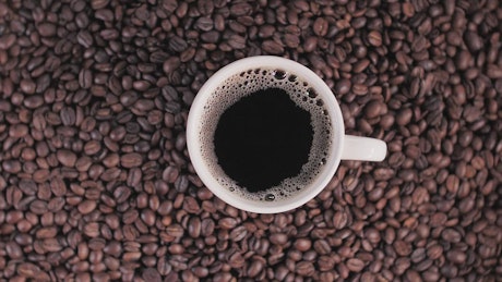 Cup of coffee on top of coffee beans.