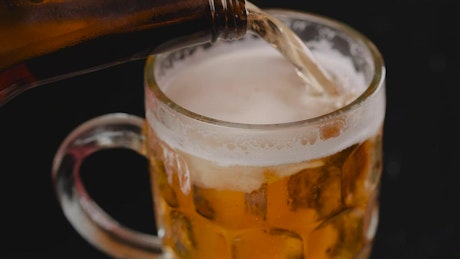 Filling a mug with beer on a dark background.