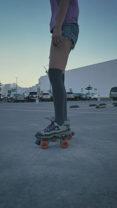 Girl skating slowly in a parking lot.