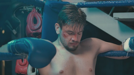 Injured boxer sitting in the ring.
