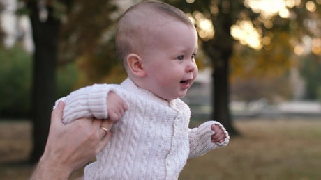 Little baby walking helped by his father.