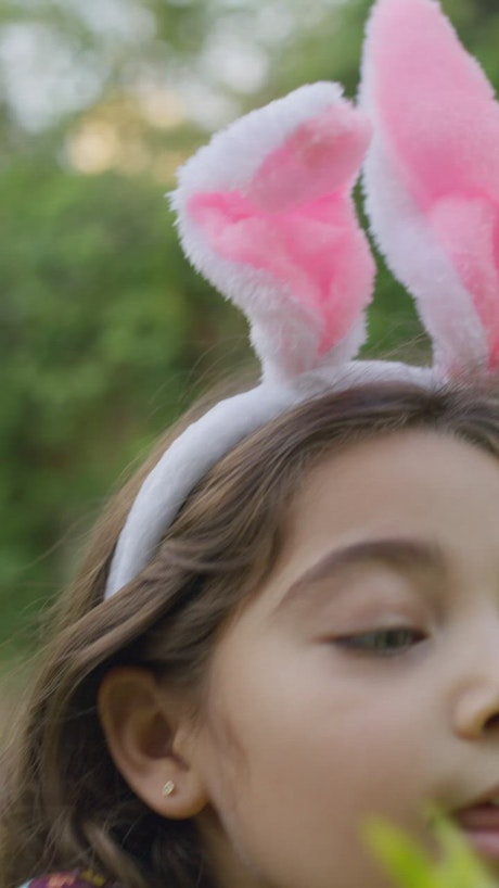 Little girl searching for an easter egg surprise in the garden bush.