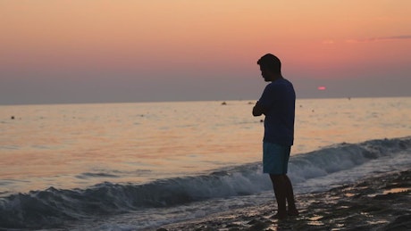 Lonely and brooding man on the shore of a beach.