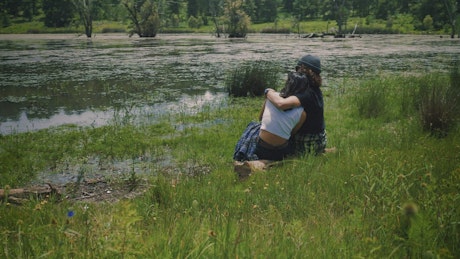 Loving couple sitting on the shore of a lake outdoors.