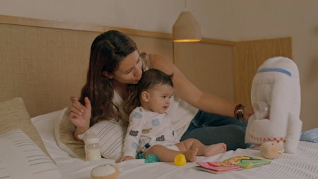 Loving mother and her baby playing with soft toys.