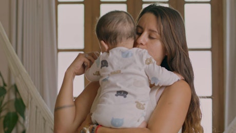 Loving mother holding and lulling her baby.