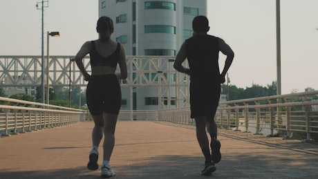 Man and woman jogging together on the street.