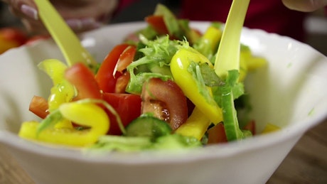 Mixing a fresh salad with oil.