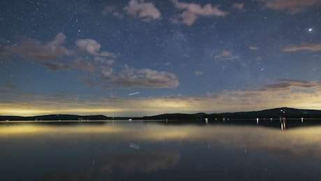 Night sky with stars at a calm lake, time lapse.