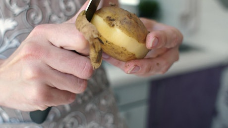 Peeling a potato with a knife.