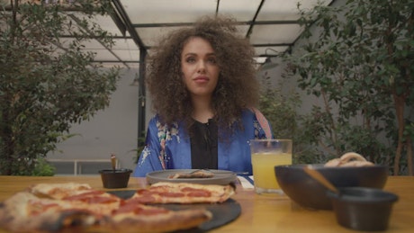 Portrait of a woman eating pizza at lunch.