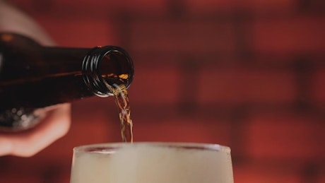 Pouring beer into a glass while the foam overflows.