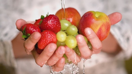Rinsing strawberries, apples and grapes holding hands.