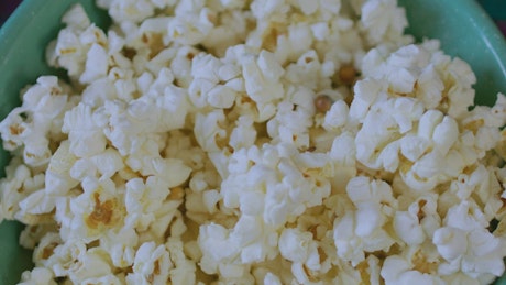 Several friends having a bowl of popcorn.