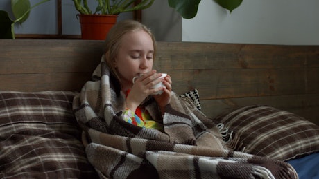 Sick girl sheltered while drinking a tea.