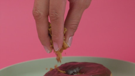 Spreading Toasted Coconut Chunks on a Donut.