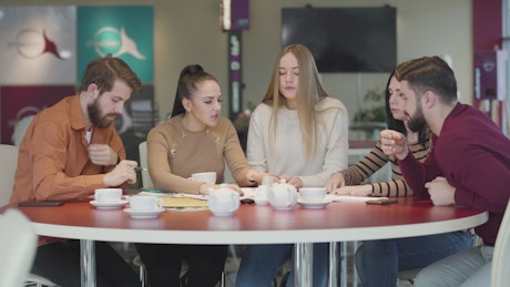 Students in a cafeteria discussing an assignment.