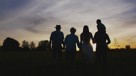 Three generations walking together at sunset.