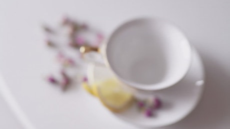 Top view of teapot pouring tea into china cup.