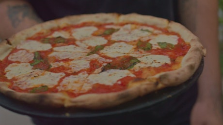 Waiter serving a pizza at a table.