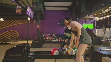 Young woman bowling with her friends.