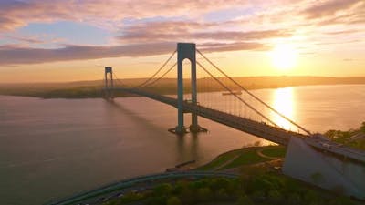 Whitestone Bridge over East River at setting sun. Sun reflecting in the calm water. .