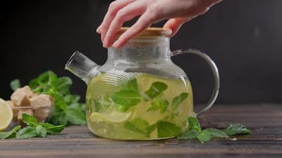 Glass Teapot with Hot Natural Organic Herbal Tea with Lemon and Mint.