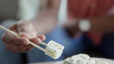 Restaurant, hand and eating sushi for lunch, closeup food and nutrition with seafood.