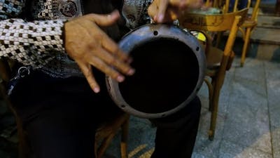 Man plays goblet drum.
