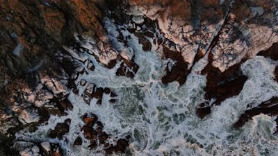 Aerial View Of Waves Crashing On Rocks.