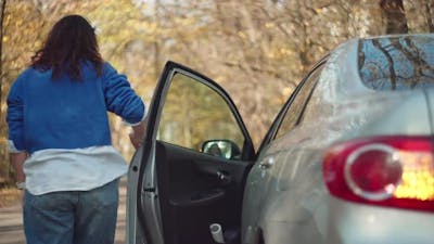 The Girl Gets Out of the Car Nervously and Looks at What is Broken in the Car.