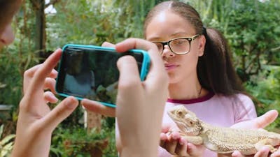 Iguana, friends and phone with girl in zoo for selfie, environment and social media.